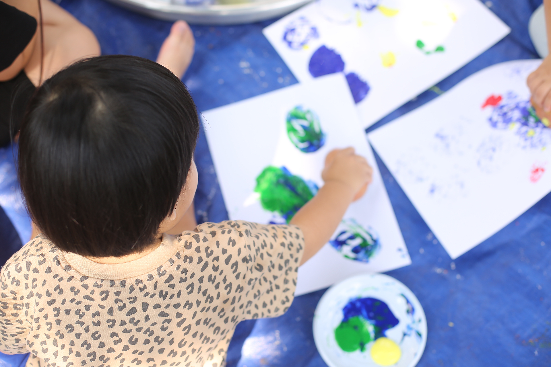 Bé tự tay vẽ tranh với màu xanh và xanh dương trong buổi messy play tại CLB Lấm Lem